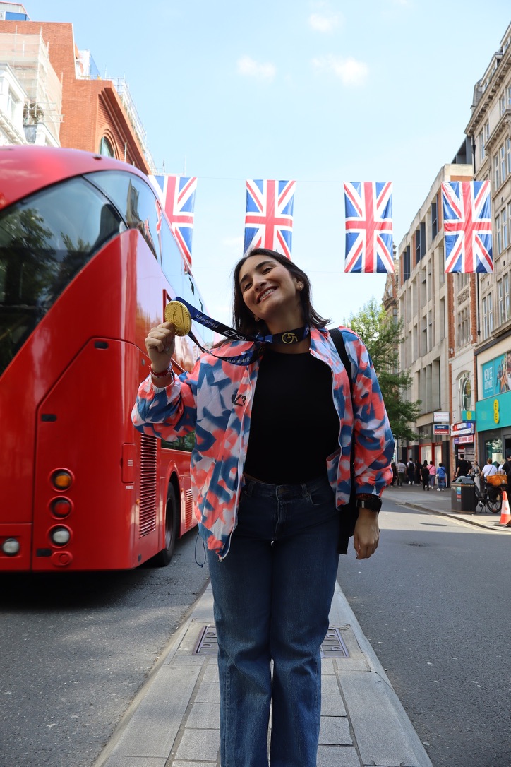 Gabi holding a race finisher medal on a London street